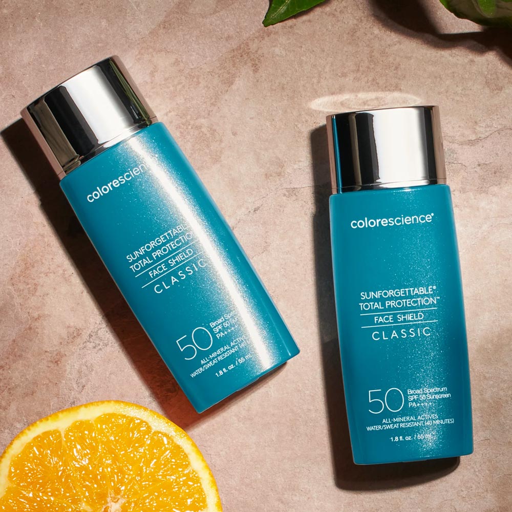Colorescience Sunforgettable Total Protection Face Shield Classic SPF 50 2 bottles and an orange slice
